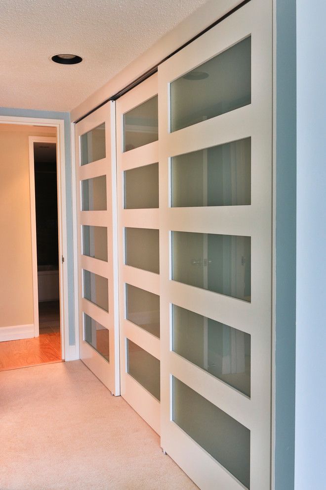 botanica white and glass sliding closet doors modernize this master bedroom  closet OENHBMR