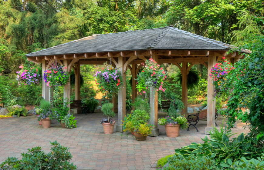 this patio gazebo houses a few benches and a number of potted plants. UAHSQXW
