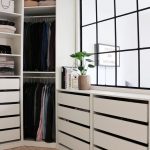 a comfy modern walk in closet with a large window and cabinets with