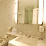 Elegant bathroom features hollywood style vanity mirror over white .