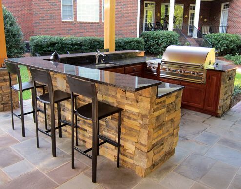 U shape outdoor kitchen island with bar top and pergola built over .