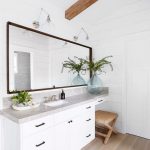 Cottage master bathroom designed with a seagrass x stool under a .