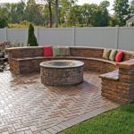 herringbone clad brick patio with a fire pit and a round bench of RTUIMKD
