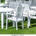 white plastic garden furniture on a lawn. - stock image NWVGTFF