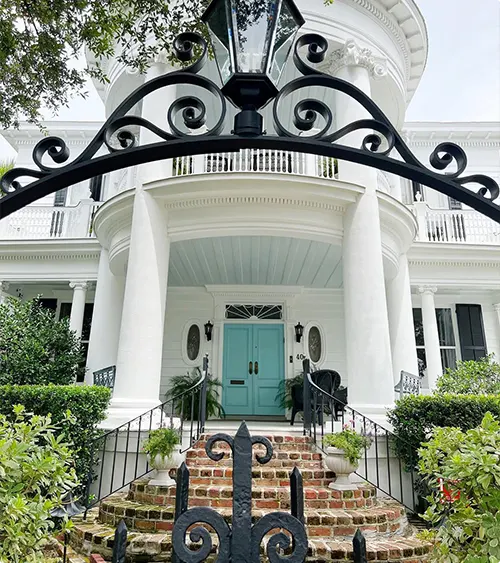 Turquoise double doors with white columns and decorative ironwork
