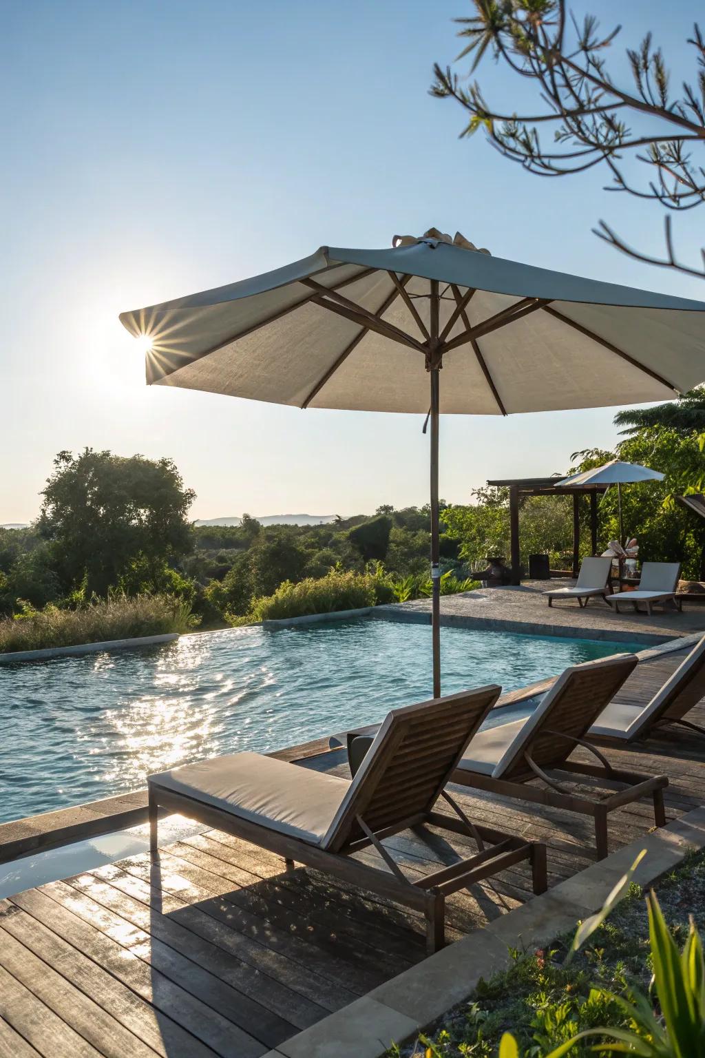 Lounge chairs shaded by a large poolside umbrella.